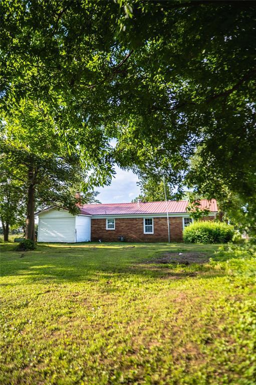 216 Patty Lynn Dr, Kennett, MO 63857 - view of front of house with a front yard, metal roof, and an attached garage