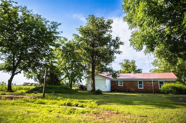 216 Patty Lynn Dr, Kennett, MO 63857 - view of side of property featuring a lawn, brick siding, and metal roof