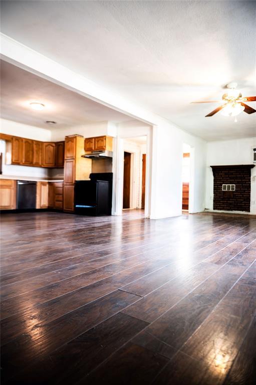 216 Patty Lynn Dr, Kennett, MO 63857 - unfurnished living room with a ceiling fan, dark wood-style flooring, and a brick fireplace