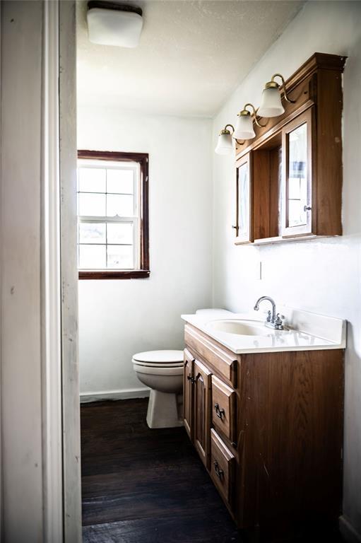 216 Patty Lynn Dr, Kennett, MO 63857 - bathroom with vanity, toilet, wood finished floors, and baseboards