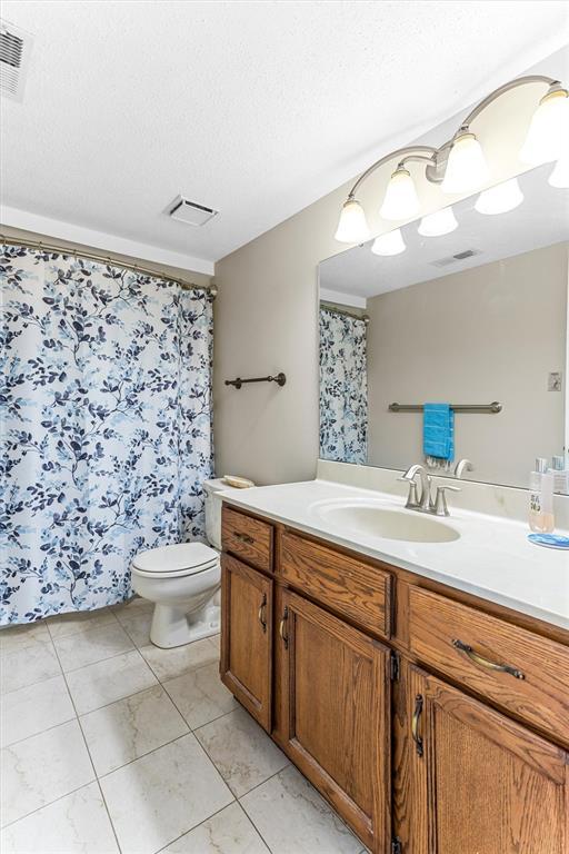 15017 Baxter Vlg Unit B, Chesterfield, MO 63017 - full bathroom featuring vanity, toilet, a textured ceiling, and a shower with shower curtain