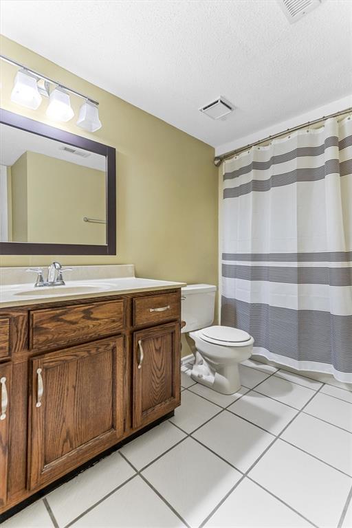 15017 Baxter Vlg Unit B, Chesterfield, MO 63017 - bathroom with toilet, vanity, tile patterned floors, a textured ceiling, and a shower with shower curtain