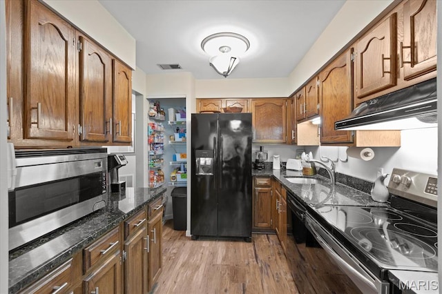 1001 Windstream Dr Unit 32, Saint Peters, MO 63376 - kitchen featuring stainless steel appliances, under cabinet range hood, a sink, dark stone countertops, and light wood-type flooring