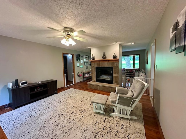 12185 Oak Meadow Dr, Rolla, MO 65401 - living area featuring wood finished floors, a glass covered fireplace, a ceiling fan, and a textured ceiling