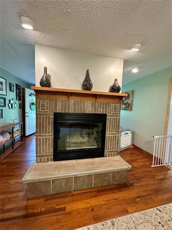 12185 Oak Meadow Dr, Rolla, MO 65401 - detailed view of a brick fireplace, wood finished floors, a textured ceiling, and baseboards