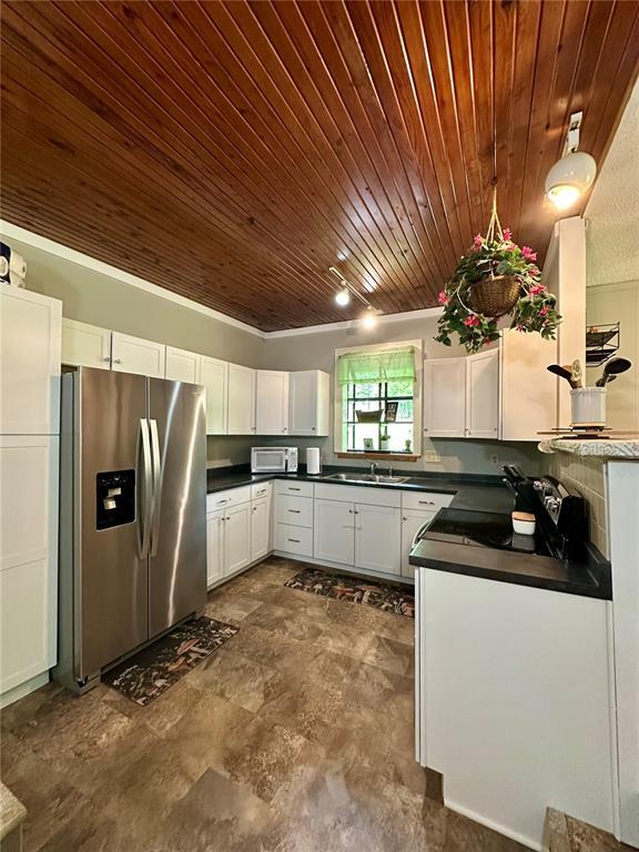 12185 Oak Meadow Dr, Rolla, MO 65401 - kitchen featuring stainless steel refrigerator with ice dispenser, wood ceiling, dark countertops, and white cabinetry