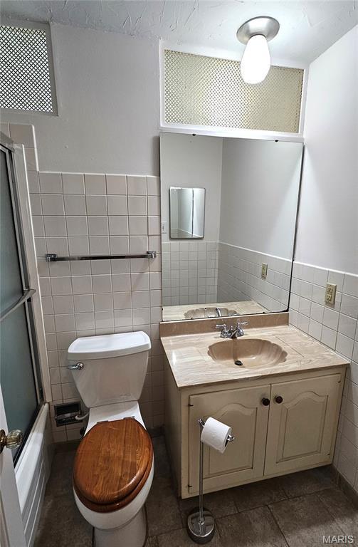 9117 Tiber Ct, Affton, MO 63123 - full bath featuring tile walls, vanity, enclosed tub / shower combo, and tile patterned floors