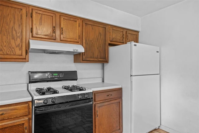 8800 Country Ln, Troy, IL 62294 - kitchen featuring gas range oven, under cabinet range hood, freestanding refrigerator, light countertops, and brown cabinets