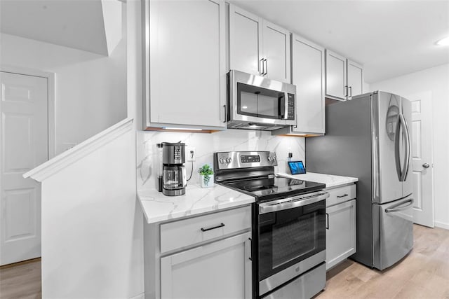 369 Tiber Pl, Saint Charles, MO 63301 - kitchen with appliances with stainless steel finishes, light wood-type flooring, light stone counters, and backsplash