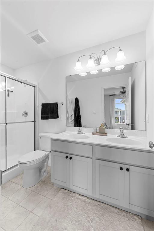 369 Tiber Pl, Saint Charles, MO 63301 - full bathroom with double vanity, a shower stall, toilet, and tile patterned floors