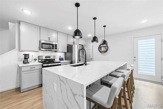 369 Tiber Pl, Saint Charles, MO 63301 - kitchen with appliances with stainless steel finishes, a sink, an island with sink, light stone countertops, and recessed lighting