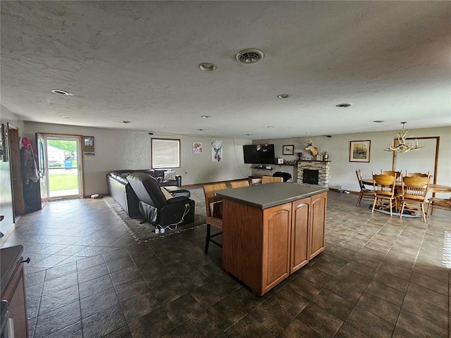 202 Jeremiah, Willisville, IL 62997 - kitchen with a fireplace, open floor plan, brown cabinetry, a kitchen bar, and a textured ceiling