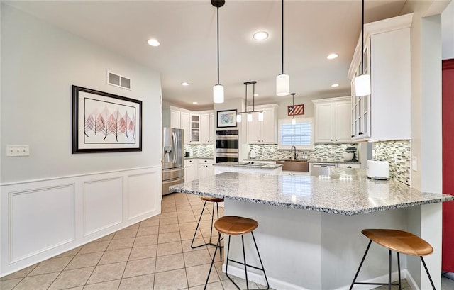 1087 Nooning Tree Dr, Chesterfield, MO 63017 - kitchen featuring stainless steel appliances, a peninsula, a sink, decorative backsplash, and a breakfast bar