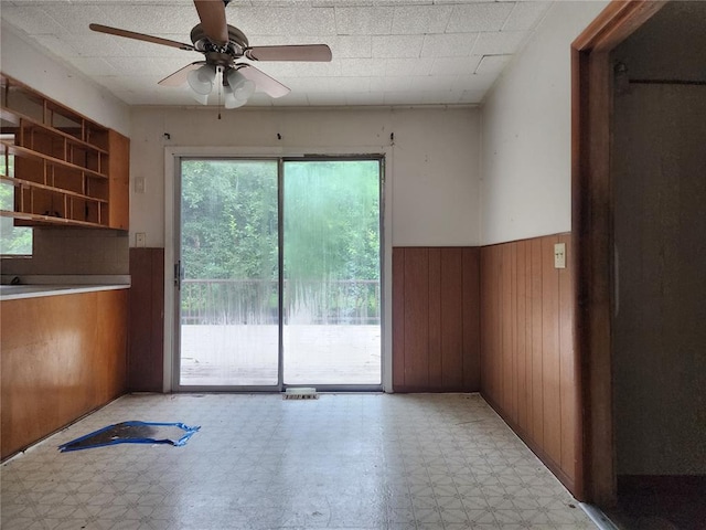 1505 Dale St, Van Buren, MO 63965 - unfurnished dining area featuring light flooring, wainscoting, wooden walls, a ceiling fan, and plenty of natural light
