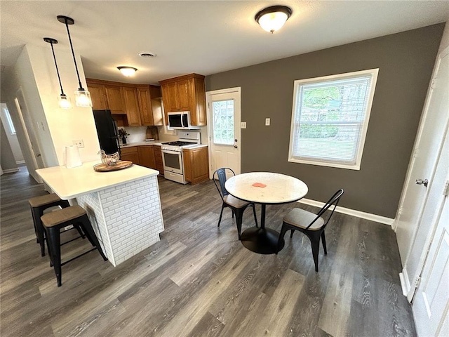436 S 5th St, Caseyville, IL 62232 - kitchen with white appliances, a peninsula, brown cabinetry, light countertops, and a kitchen breakfast bar