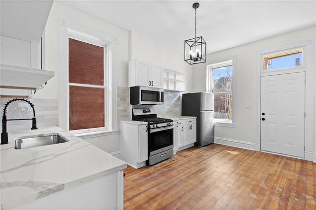 2856 Wyoming St, Saint Louis, MO 63118 - kitchen featuring stainless steel appliances, open shelves, a sink, a chandelier, and decorative backsplash