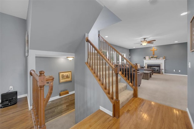 1002 Brook Mont Dr, Ofallon, MO 63366 - stairway featuring ceiling fan, a fireplace, hardwood / wood-style flooring, baseboards, and recessed lighting