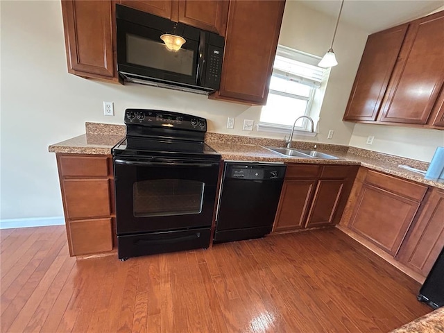 333 Bramblett Hls, Ofallon, MO 63366 - kitchen with black appliances, a sink, hardwood / wood-style flooring, decorative light fixtures, and brown cabinetry