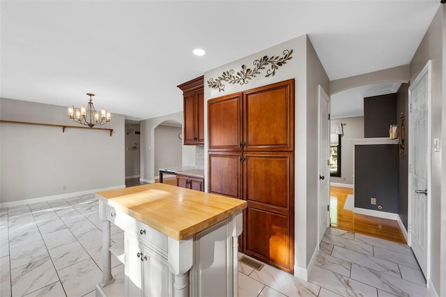 5812 Birch Hollow Dr, Oakville, MO 63129 - kitchen with arched walkways, light marble finish flooring, baseboards, a chandelier, and wood counters