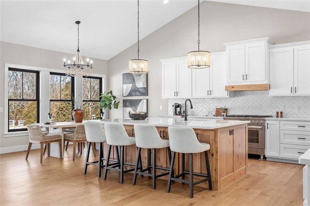 973 Buckner Rd, Wentzville, MO 63385 - kitchen featuring high end stainless steel range, a sink, a kitchen island with sink, a chandelier, and backsplash