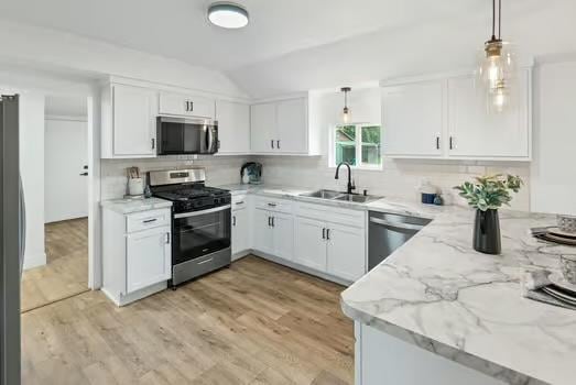 121 Douglas St, Ofallon, IL 62269 - kitchen with appliances with stainless steel finishes, a sink, vaulted ceiling, light stone counters, and tasteful backsplash