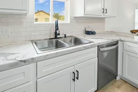 121 Douglas St, Ofallon, IL 62269 - kitchen with stainless steel dishwasher, a sink, white cabinetry, and backsplash