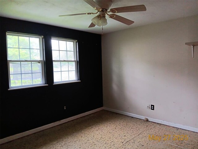 3734 Carol Park Rd, House Springs, MO 63051 - empty room featuring baseboards, dark speckled floor, healthy amount of natural light, and a ceiling fan