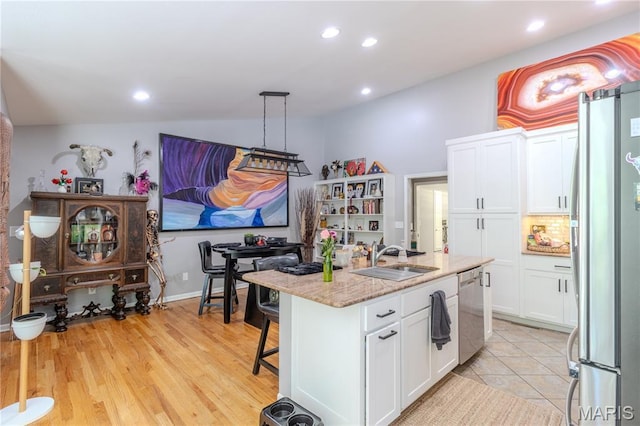 700 Lariat Ln, Rolla, MO 65401 - kitchen with stainless steel appliances, white cabinetry, recessed lighting, an island with sink, and light stone counters