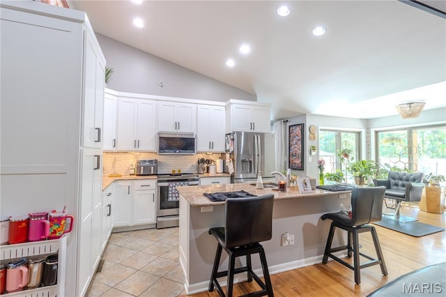 700 Lariat Ln, Rolla, MO 65401 - kitchen featuring stainless steel appliances, tasteful backsplash, a center island with sink, white cabinetry, and a breakfast bar