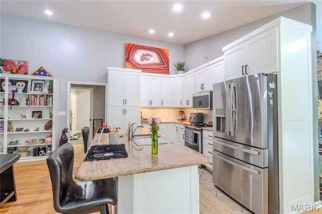 700 Lariat Ln, Rolla, MO 65401 - kitchen with stainless steel appliances, white cabinetry, decorative backsplash, recessed lighting, and a kitchen bar