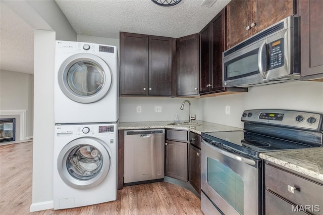 1447 Oriole Pl, Brentwood, MO 63144 - kitchen with appliances with stainless steel finishes, stacked washer / drying machine, light wood-type flooring, a sink, and dark brown cabinets