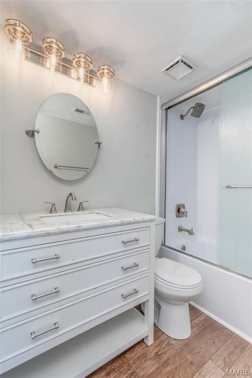 1447 Oriole Pl, Brentwood, MO 63144 - bathroom featuring vanity, wood finished floors, toilet, and combined bath / shower with glass door