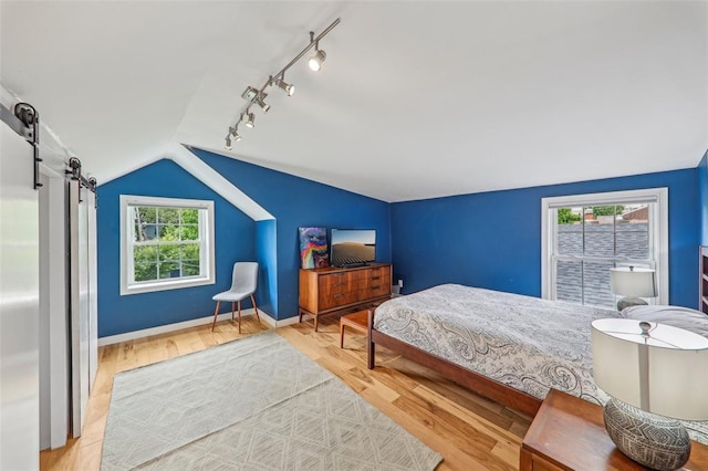 6708 Etzel Ave, University City, MO 63130 - bedroom with vaulted ceiling, rail lighting, a barn door, wood finished floors, and baseboards