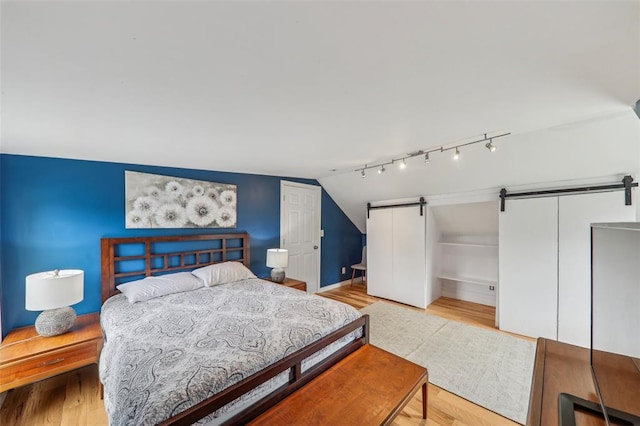 6708 Etzel Ave, University City, MO 63130 - bedroom featuring a barn door, vaulted ceiling, wood finished floors, and baseboards