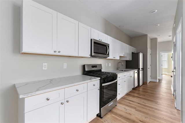 3535 Giles Ave, Saint Louis, MO 63116 - kitchen featuring stainless steel appliances, a sink, light wood-type flooring, white cabinetry, and recessed lighting