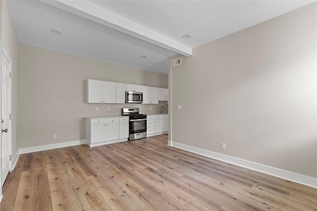 3535 Giles Ave, Saint Louis, MO 63116 - unfurnished living room with baseboards, light wood-style flooring, beam ceiling, and a sink