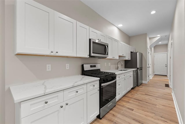 3535 Giles Ave, Saint Louis, MO 63116 - kitchen with appliances with stainless steel finishes, a sink, light wood-type flooring, white cabinetry, and recessed lighting