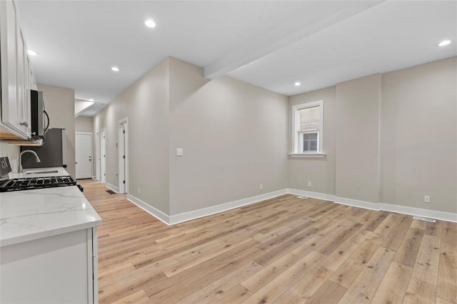 3535 Giles Ave, Saint Louis, MO 63116 - kitchen featuring stainless steel microwave, light wood-style floors, white cabinetry, baseboards, and light stone counters