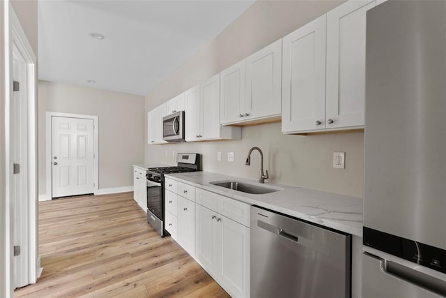 3535 Giles Ave, Saint Louis, MO 63116 - kitchen featuring stainless steel appliances, a sink, light wood finished floors, white cabinets, and light stone countertops