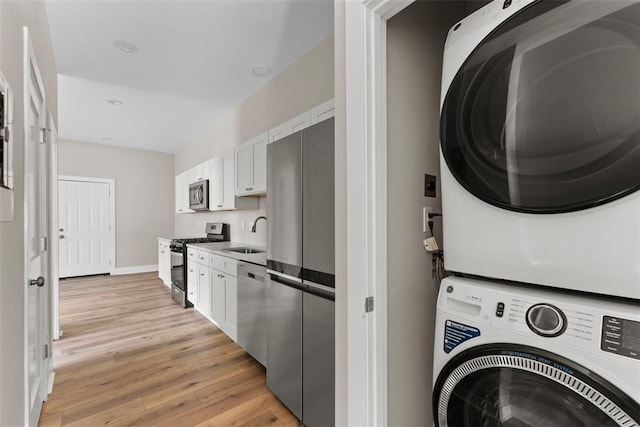3535 Giles Ave, Saint Louis, MO 63116 - laundry room featuring stacked washing machine and dryer, light wood-type flooring, and baseboards