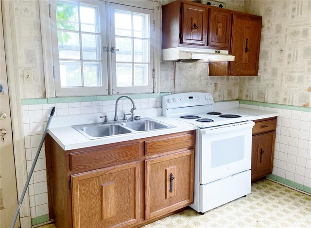 708 E State Route 72, Rolla, MO 65401 - kitchen with white electric stove, wallpapered walls, under cabinet range hood, a sink, and tile walls
