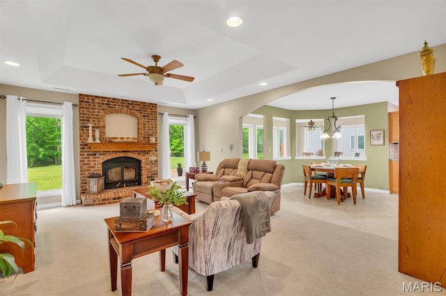 61 Serenity Ln, Troy, MO 63379 - living room featuring light carpet, a ceiling fan, arched walkways, a tray ceiling, and a fireplace