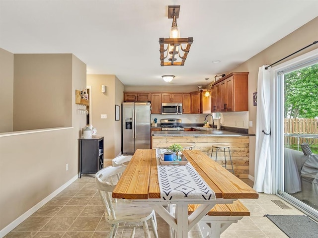 628 Hailie St, Saint Libory, IL 62282 - kitchen with stainless steel appliances, a sink, light tile patterned floors, brown cabinets, and baseboards