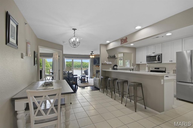 4800 Eagleview Dr Unit 113B, Osage Beach, MO 65065 - kitchen with appliances with stainless steel finishes, a kitchen breakfast bar, white cabinetry, a chandelier, and decorative backsplash