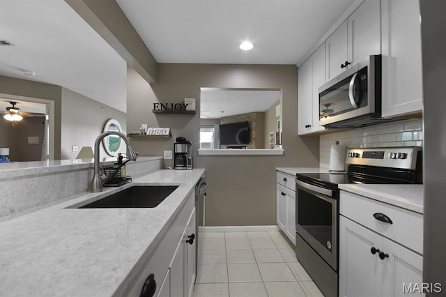 4800 Eagleview Dr Unit 113B, Osage Beach, MO 65065 - kitchen featuring stainless steel appliances, a sink, decorative backsplash, light tile patterned floors, and ceiling fan