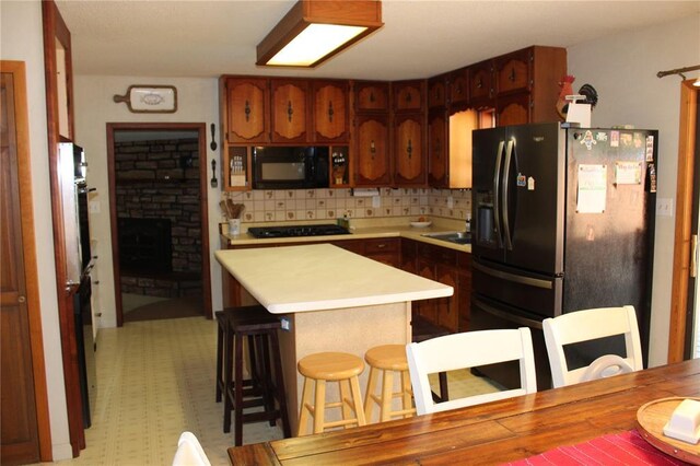 20143 State Highway 34, Piedmont, MO 63957 - kitchen with black appliances, light countertops, tasteful backsplash, a sink, and a breakfast bar area