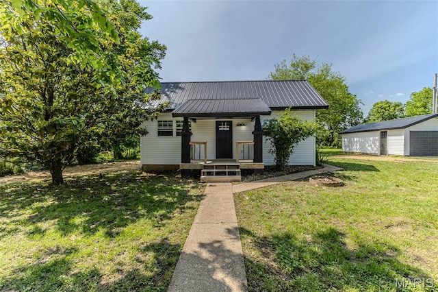 711 Noe Dr, Richland, MO 65556 - bungalow-style home with a detached garage, a porch, a front yard, and metal roof