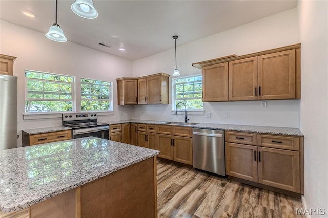 711 Noe Dr, Richland, MO 65556 - kitchen featuring appliances with stainless steel finishes, a sink, light wood-type flooring, light stone counters, and decorative light fixtures