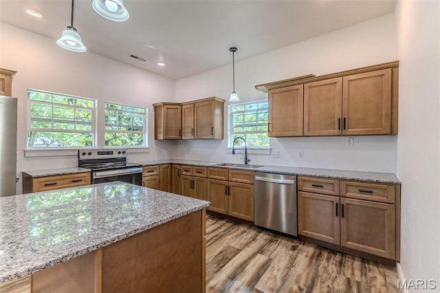 711 Noe Dr, Richland, MO 65556 - kitchen featuring appliances with stainless steel finishes, a sink, light stone countertops, decorative light fixtures, and light wood-type flooring