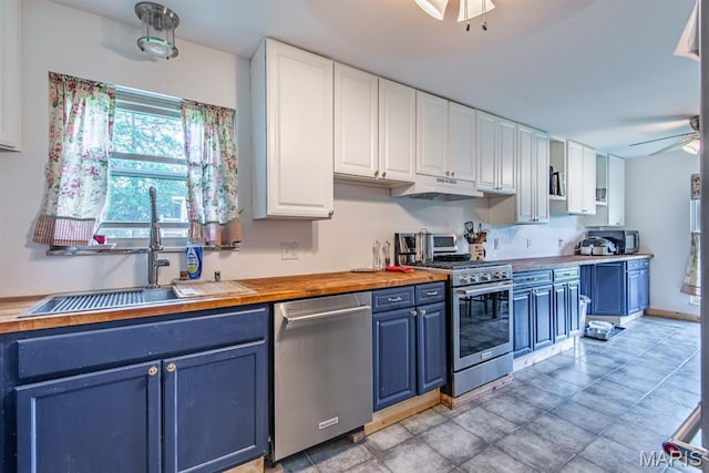 1956 Parkton W Dr, Barnhart, MO 63012 - kitchen with blue cabinets, stainless steel appliances, white cabinetry, under cabinet range hood, and butcher block countertops